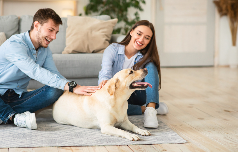Young family of two sitting on floor with dog